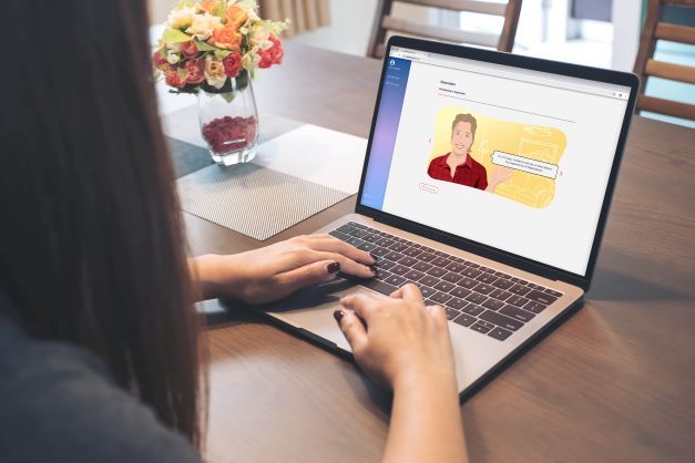 A woman with should length brown hair is sitting at their computer looking at a Just a Thought course on screen