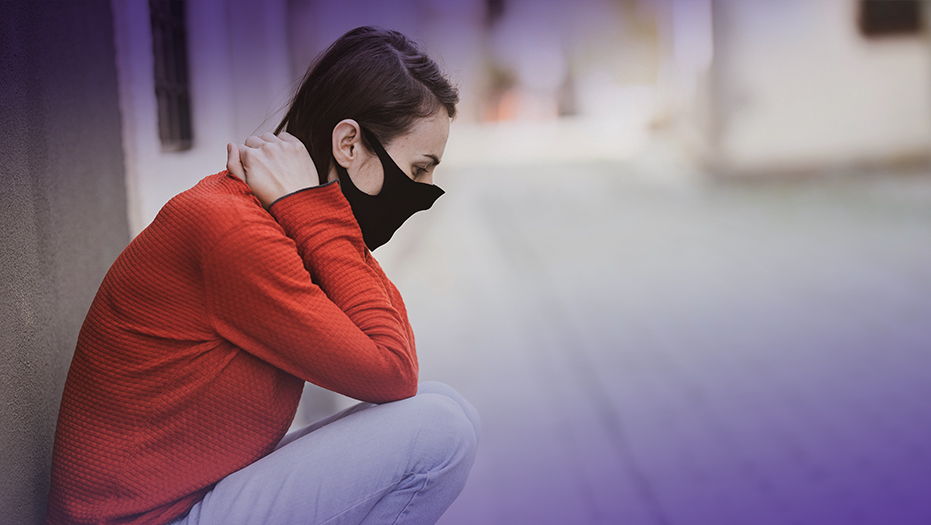 Woman wearing face mask looking distressed.